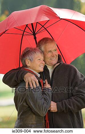 Senior couple using a red umbrella View Large Photo Image Picture - Senior couple using a red umbrella. Fotosearch
