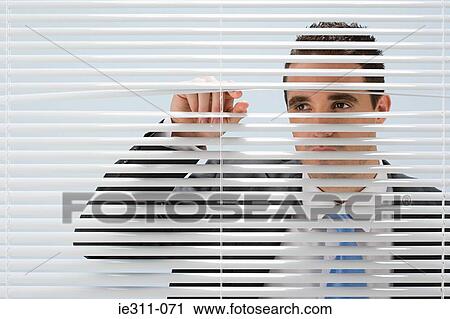 Stock Image - Man looking through blinds. Fotosearch