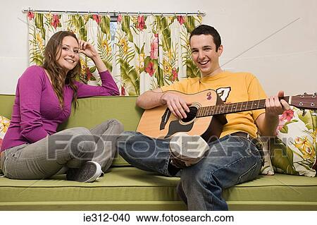 Stock Image - A teenage boy playing a guitar for a teenage girl. Fotosearch