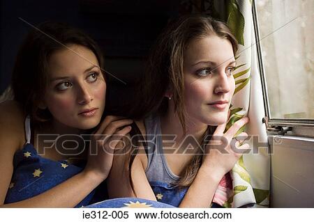Two teenage girls looking out of a window View Large Photo Image Stock Photography - Two teenage girls looking out of a window. Fotosearch