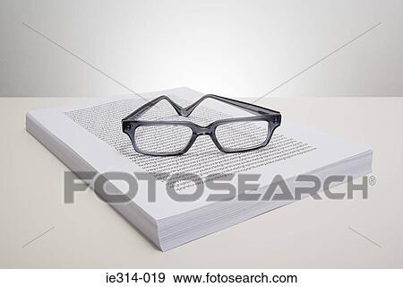 Stock Photo - Eyeglasses and a stack of paper . Fotosearch