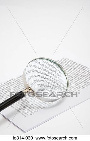 Stock Image - Magnifying glass and a stack of paper. Fotosearch