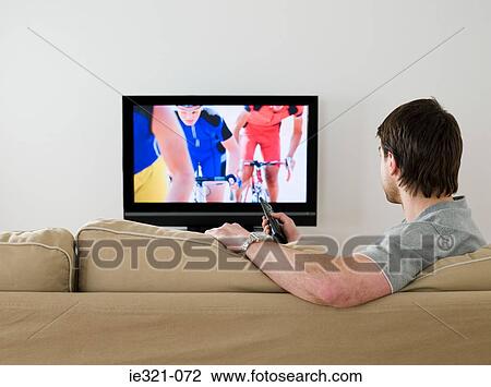 Stock Image - A man watching cycling on the tv. Fotosearch