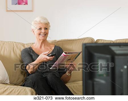 Stock Image - A senior woman watching tv. Fotosearch