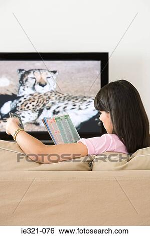 Stock Photograph - A woman reading a tv listings magazine. Fotosearch
