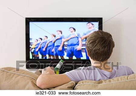 Stock Image - A young man watching a football match. Fotosearch