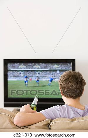 A young man watching a football match View Large Photo Image Stock Image - A young man watching a football match. Fotosearch