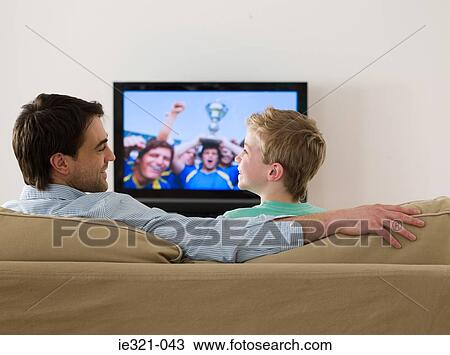 Father and son watching a football match View Large Photo Image Stock Image - Father and son watching a football match. Fotosearch