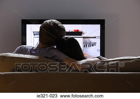 Rear view of a couple watching tv View Large Photo Image Stock Image - Rear view of a couple watching tv. Fotosearch