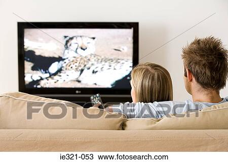 Rear view of a couple watching tv View Large Photo Image Stock Image - Rear view of a couple watching tv. Fotosearch