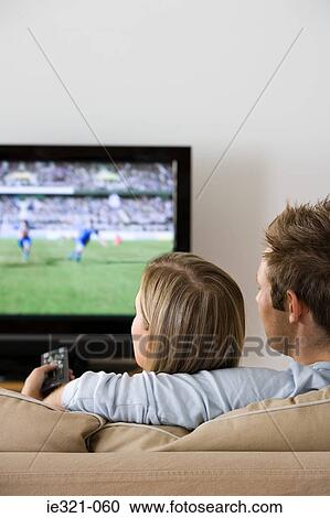 Rear view of a couple watching tv View Large Photo Image Stock Image - Rear view of a couple watching tv. Fotosearch