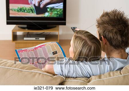 Rear view of a couple watching tv View Large Photo Image Stock Photo - Rear view of a couple watching tv. Fotosearch