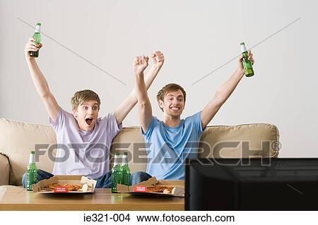 Two young men cheering at the tv View Large Photo Image Picture - Two young men cheering at the tv. Fotosearch