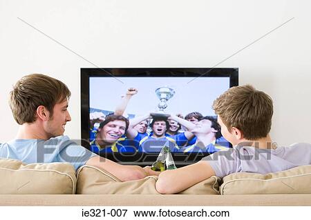 Two young men watching football on the tv View Large Photo Image Stock Photo - Two young men watching football on the tv. Fotosearch