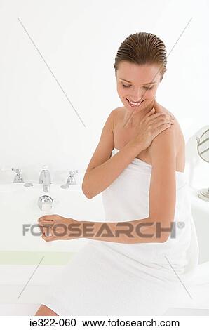 Stock Image - A woman applying moisturiser to her shoulder. Fotosearch