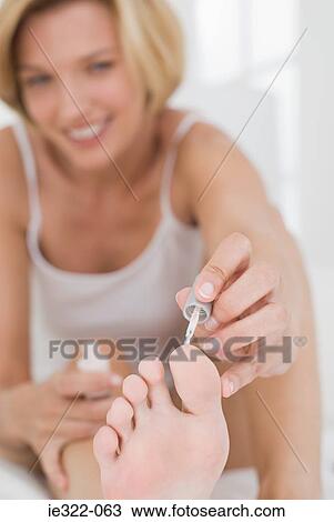 Stock Image - A woman applying nail polish to her toenails. Fotosearch