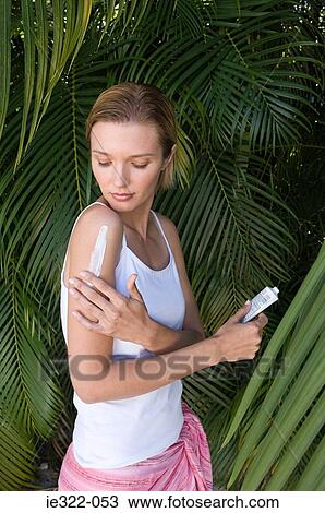 Stock Image - A woman moisturising her arm. Fotosearch