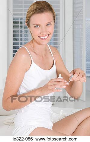 Stock Photograph - A woman painting her nails. Fotosearch