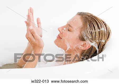 Stock Image - A woman splashing water on her face. Fotosearch