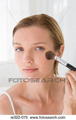 Stock Photography - A young woman applying blusher. Fotosearch