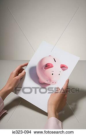 Picture - A woman holding a photograph of a piggy bank. Fotosearch