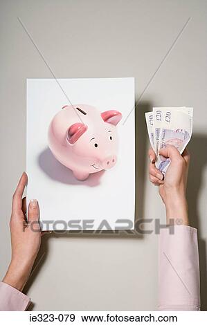 Stock Photo - A woman holding a photograph of a piggy bank and money. Fotosearch