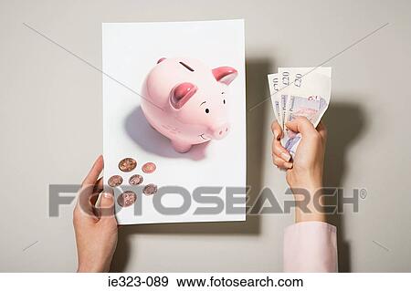 A woman holding a photograph of a piggy bank and money View Large Photo Image Stock Photo - A woman holding a photograph of a piggy bank and money. Fotosearch