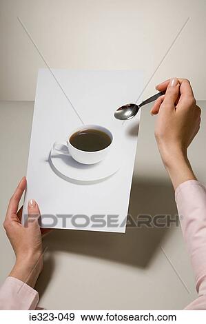 A woman holding a photograph of a coffee cup and a spoon View Large Photo Image Stock Photo - A woman holding a photograph of a coffee cup and a spoon. Fotosearch
