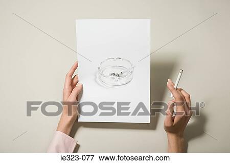 Stock Photo - A woman holding a photograph of an ashtray and a cigarette. Fotosearch