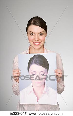 A woman holding a photograph of herself looking sad View Large Photo Image Stock Photo - A woman holding a photograph of herself looking sad. Fotosearch