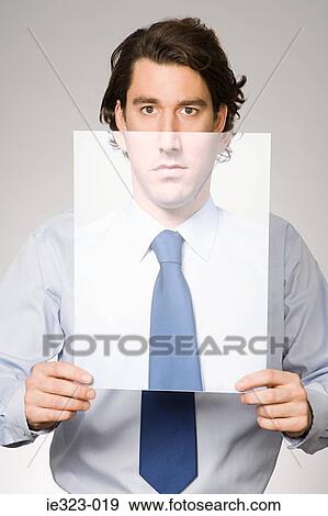 Portrait of a man holding a photograph of himself View Large Photo Image Stock Photo - Portrait of a man holding a photograph of himself. Fotosearch