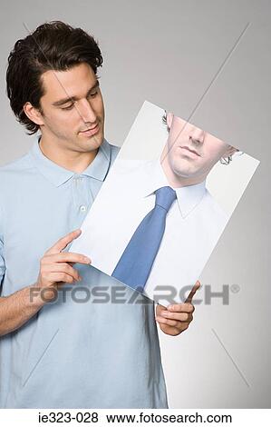 Portrait of a man holding a photograph of himself View Large Photo Image Stock Photo - Portrait of a man holding a photograph of himself. Fotosearch