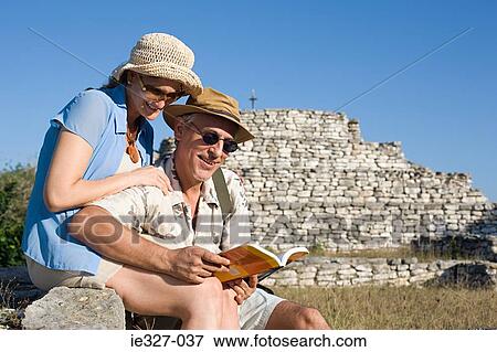 Couple by ruins with guidebook View Large Photo Image Stock Photo - Couple by ruins with guidebook. Fotosearch
