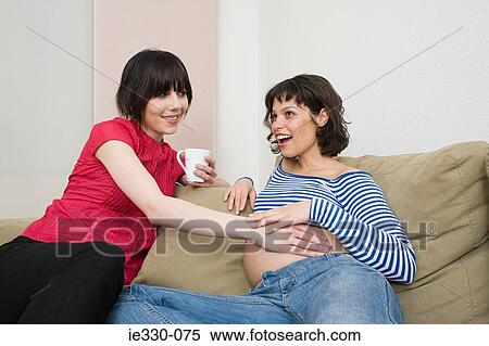 Friend touching pregnant womans stomach View Large Photo Image Stock Photography - Friend touching pregnant womans stomach. Fotosearch