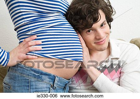 Stock Photograph - Man with head on a pregnant stomach. Fotosearch