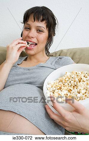 Pregnant woman eating popcorn View Large Photo Image Stock Image - Pregnant woman eating popcorn. Fotosearch