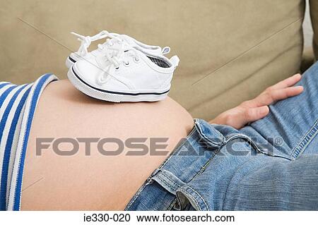 Pregnant woman with baby shoes on stomach View Large Photo Image Stock Image - Pregnant woman with baby shoes on stomach. Fotosearch