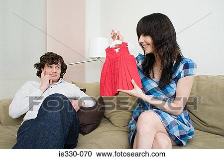 Stock Image - Woman holding baby clothes. Fotosearch