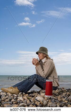 Woman having a drink on the beach View Large Photo Image Stock Photograph - Woman having a drink on the beach. Fotosearch