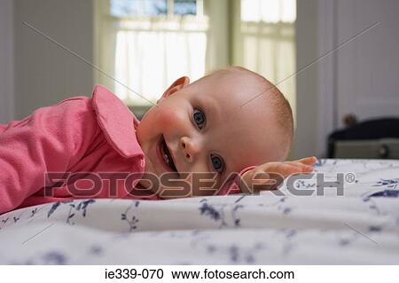 Baby lying on bed View Large Photo Image Stock Image - Baby lying on bed. Fotosearch