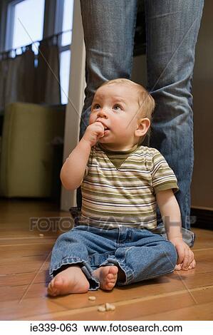 Stock Image - Baby sitting at feed of adult. Fotosearch