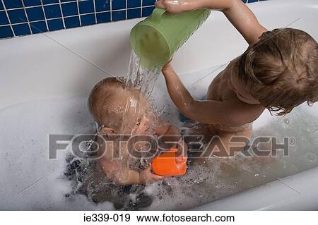 Boy pouring water over baby brother View Large Photo Image Stock Photo - Boy pouring water over baby brother. Fotosearch