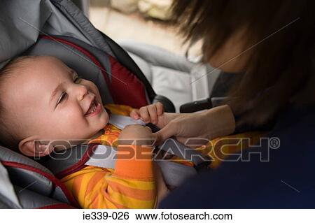 Mother putting baby in car seat View Large Photo Image Stock Photograph - Mother putting baby in car seat. Fotosearch