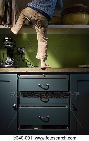 Boy climbing in kitchen View Large Photo Image Stock Image - Boy climbing in kitchen. Fotosearch