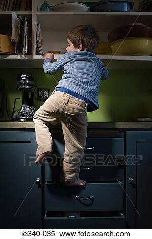 Boy climbing in kitchen View Large Photo Image Stock Photography - Boy climbing in kitchen. Fotosearch