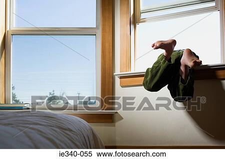 Stock Photography - Boy climbing out of window. Fotosearch