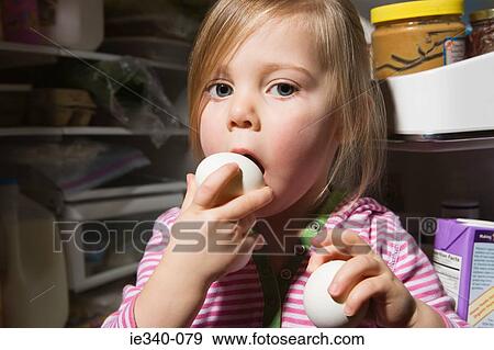 Girl trying to eat egg View Large Photo Image Stock Photo - Girl trying to eat egg. Fotosearch