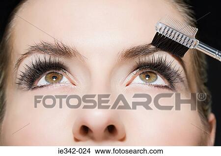 Picture - Woman brushing her eyebrows. Fotosearch