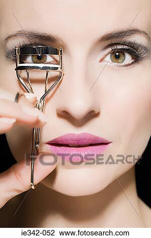 Woman curling eyelashes View Large Photo Image Stock Image - Woman curling eyelashes. Fotosearch