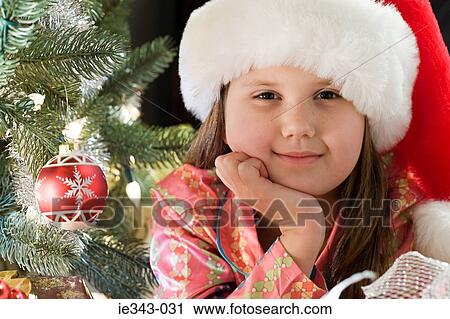 Stock Image - Girl by christmas tree. Fotosearch